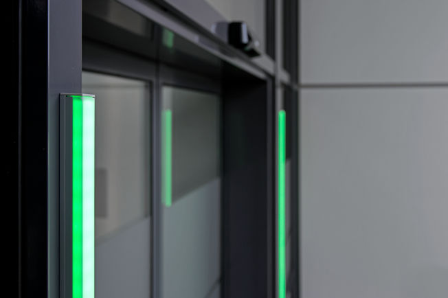 O sinal visual verde na porta automática sinaliza que a pessoa pode entrar no edifício.