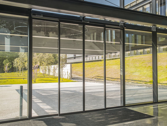 GEZE-Türsysteme im neuen Hauptsitz von Furla Der Slimdrive SL NT in Schwarz fügt sich mit seiner geringen Bauhöhe von nur 7 cm perfekt in das minimalistische Designkonzept des Gebäudes ein.