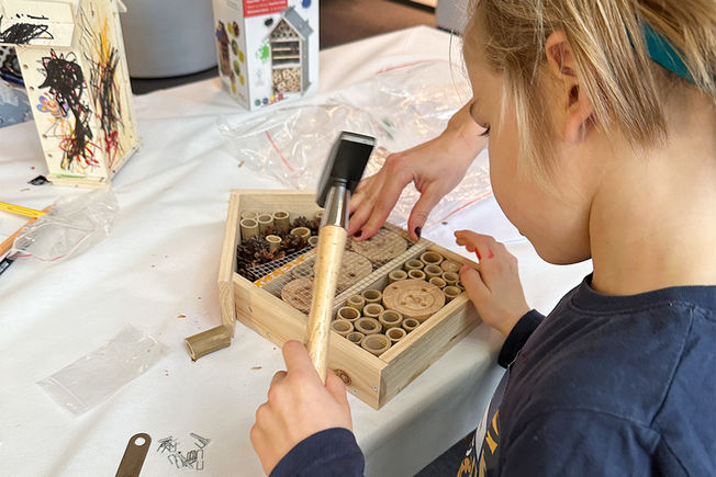 Child at the GEZE honey harvesting event makes an insect hotel