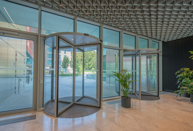 GEZE ITA - HQ Deloitte - focus on the lobby entrance Focused interior view of the main lobby entrance, with a central plant enhancing the sense of openness, balance and welcoming elegance.