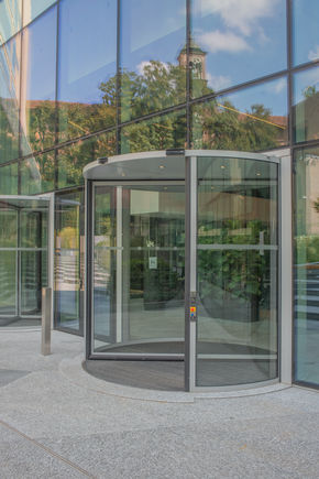 GEZE ITA - Deloitte HQ - exterior view of the lobby with double Revo.Prime Exterior view of the lobby featuring double Revo.Prime revolving doors, with a close-up on the first automatic door, conveying a modern, welcoming and elegant entrance