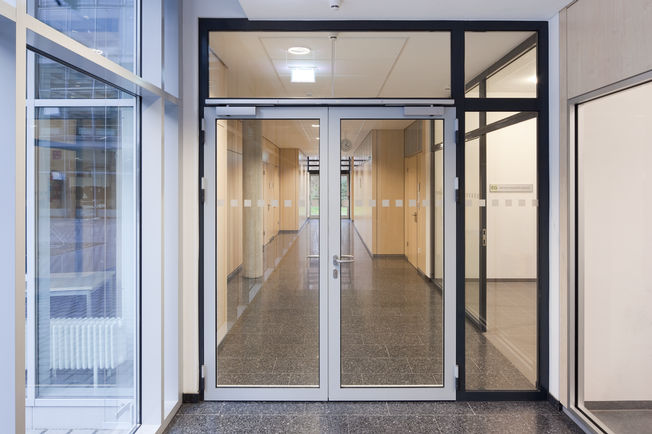 Felső szerelésű, csúszósínes ajtózár TS 5000 R-ISM Tűzszakaszajtó TS 5000 R-ISM-mel, csúszósínes ajtócsukó rendszer kétszárnyú ajtókhoz csukássorrend szabályozással és füstkapcsolóval, a frierichshafeni szakközépiskolában.