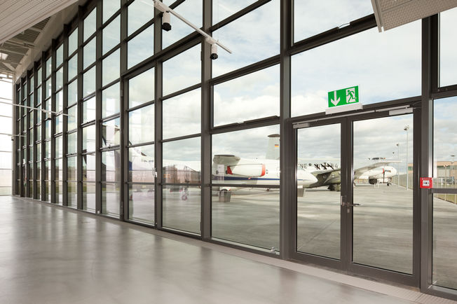 Felső szerelésű, csúszósínes ajtózár TS 5000 L-ISM, beépítve a friedrichshafeni Dorniermuseumban. Felső szerelésű, csúszósínes ajtózár rendszer, pánttal ellentétes oldalon, kétszárnyú ajtókhoz antipánik funkcióval és csukássorrend szabályozással.