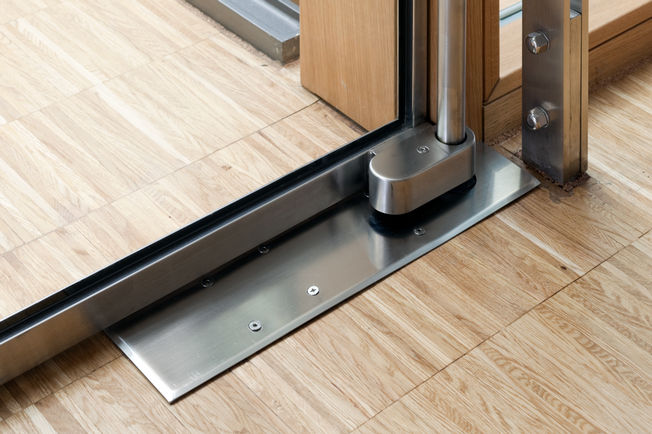 För golvmonterade dörrstängare sitter stängningssekvensmekaniken normalt i en box i golvet mellan dörrelementet, vilket ger en elegant visuell lösning. 