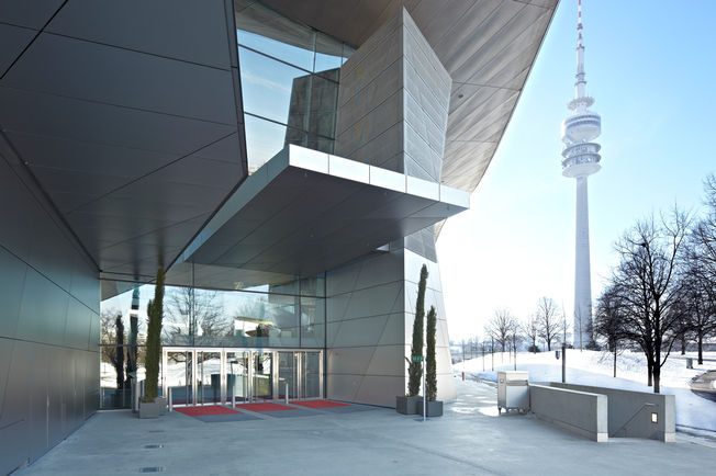 Sustav gornjeg zatvarača vrata s kliznom vodilicom - TS 5000 L + pogon zaokretnih vrata TSA 160 NT, BMW Welt TS 5000 L pruža praktičnost hodanja posjetitelju, jer se teška vrata prilikom sklapanja koče i na taj način se skoro bešumno zatvaraju. Ovi se atributi također susreću kod TSA 160 NT samo ako je s njim ugrađena još i funkcija Push & Go.