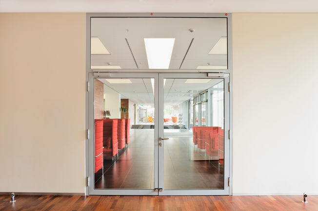 Overhead door closer with guide rail system TS 5000 ISM, installed at the Rheinlandhaus in Cologne. Door closer for double leaf doors with closing sequence control and with integrated back check, which causes the strongly opened doors to be slowed down.