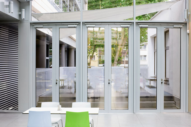 Felső szerelésű, csúszósínes ajtózár TS 5000 L-ISM, beépítve Kölnben, a Rheinlandhausban. Felső szerelésű, csúszósínes ajtózár rendszer, pánttal ellentétes oldalon, kétszárnyú ajtókhoz antipánik funkcióval és csukássorrend szabályozással.