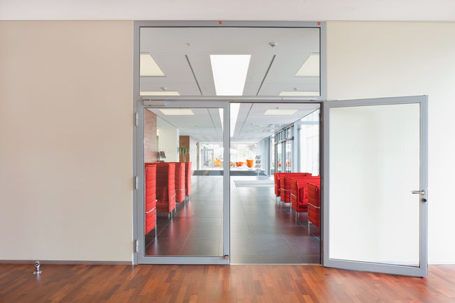 Bovenliggende deurdranger met glijrail TS 5000 ISM, geïnstalleerd in het Rheinlandhaus in Keulen. Deurdranger voor tweevleugellige deuren met sluitvolgorderegeling en geïntegreerde openingsdemping, waardoor krachtig uitzwaaiende deuren worden afgeremd.