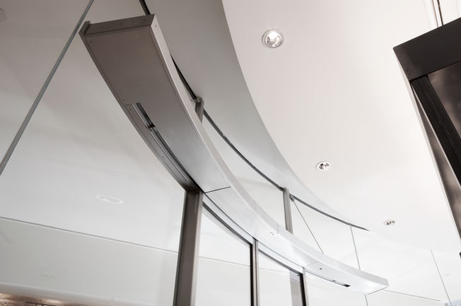 Automatski sustav polukružnih kliznih vrata odnosno kružnih kliznih vrata Slimdrive SC Automatski sustav polukružnih kliznih vrata odnosno kružnih kliznih vrata Slimdrive SC, ugrađen u Belgian Sky Shop Brussels International Airport, snimka izbliza.