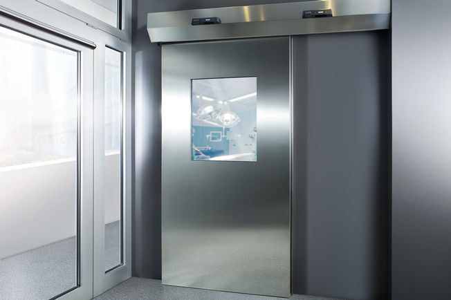 sistema di porta scorrevole Powerdrive PL-HT, qui in un ospedale sistema di porta scorrevole lineare automatico per grandi porte pesanti in aree con requisiti igienici elevati.