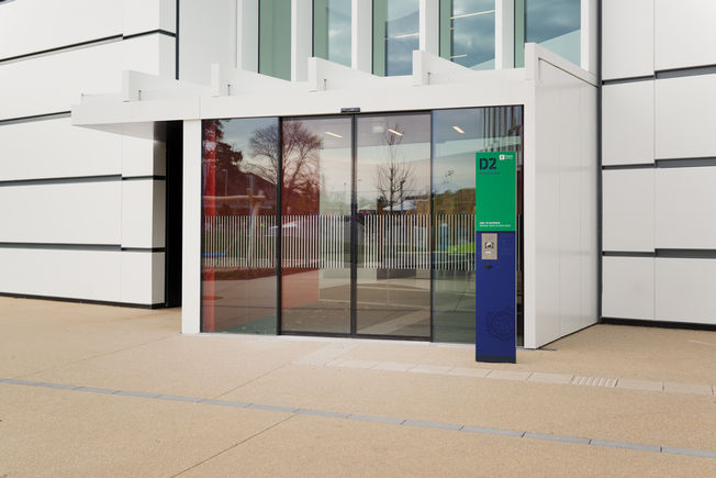Slimdrive SL-FR con sistema todo vidrio integrado (IGG) en el centro educativo Sistema de puerta corredera automática Slimdrive SL-FR con sistema todo vidrio integrado (IGG) para vías de evacuación y emergencia para su uso en las fachadas de vidrio más estrechas, instalado en la Universidad de Economía de Viena.