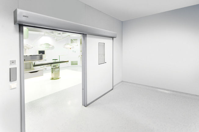 Drive solution GEZE Powerdrive PL-HT kit in an operating room door Automatic linear sliding door system for large heavy doors in areas with increased hygiene demands