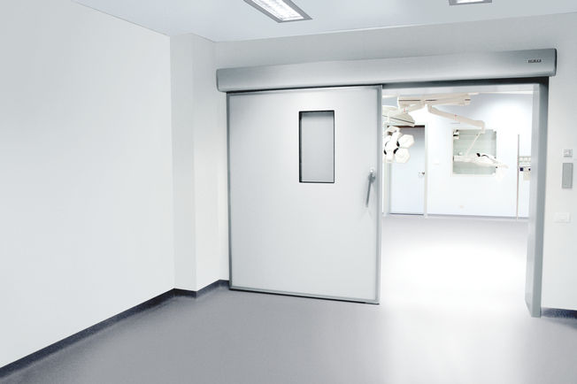 Drive solution GEZE Powerdrive PL-HT kit, installed in a hospital ward Automatic linear sliding door system for large heavy doors in areas with increased hygiene demands
