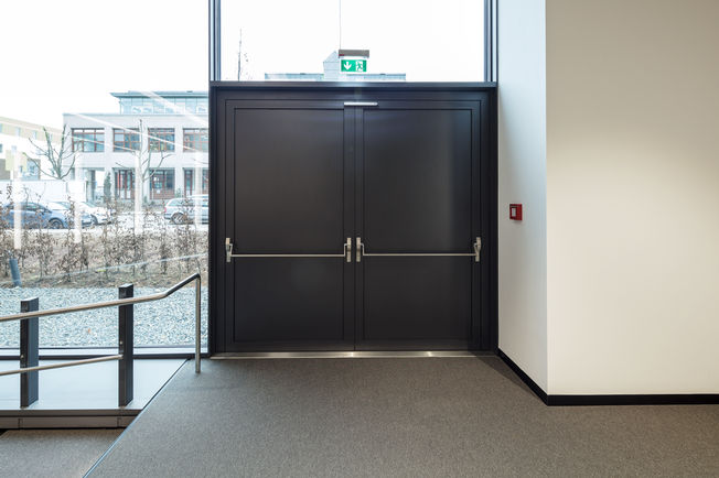 Anche le porte di fuga antipanico totale a due ante sono integrate nel building management technology. Foto: Jürgen Pollak per GEZE GmbH