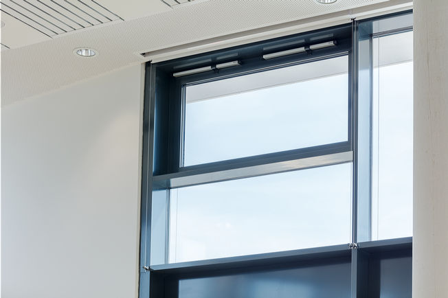 Soluzione con sistema di evacuazione fumo e calore collegata in rete e ventilazione dell’edificio intelligente: finestre a soffitto automatiche nella sala consiliare