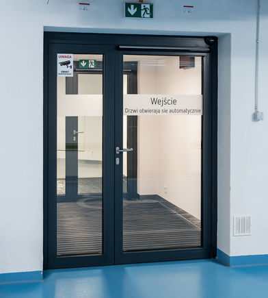Automatismo para puerta batiente Slimdrive EMD-F IS en la clínica Medicus en Wrocławiu, Polonia Sistema de automatismo para puerta batiente electromecánico para puertas cortafuegos de doble hoja con secuencia de cierre y sensor de humo integrado