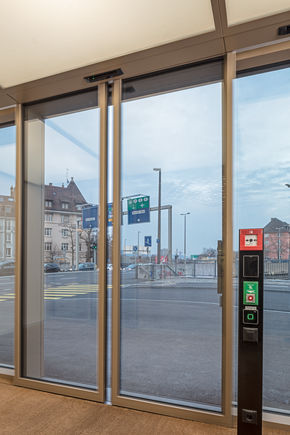 Skjutdörrsautomatik Powerdrive PL-FR med manöverpelare för brytarna vid entrén till Grosspetertower i Zürich Automatiskt skjutdörrssystem i utrymnings- och räddningsvägar för stora och tunga dörrar