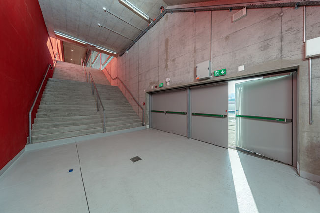 Nødudgang Tissot Arena Biel med RWA K 600 Tissot Arena Biels trappe og nødudgang med vippearmdrev RWA K 600 på 2-fløjet dør med lukkesekvensregulering.