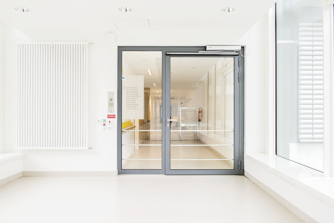 Napęd drzwi rozwieranych GEZE – Slimdrive EMD-F ze sterownikiem drzwi ewakuacyjnych TZ 320 w placówce medycznej Olgahospital/Frauenklinik w Stuttgarcie