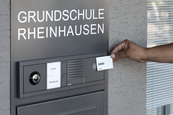 RFID Ausweiskarte MIFARE wird an den GEZE INAC Leser am Eingang der Grundschule Rheinhausen gehalten.