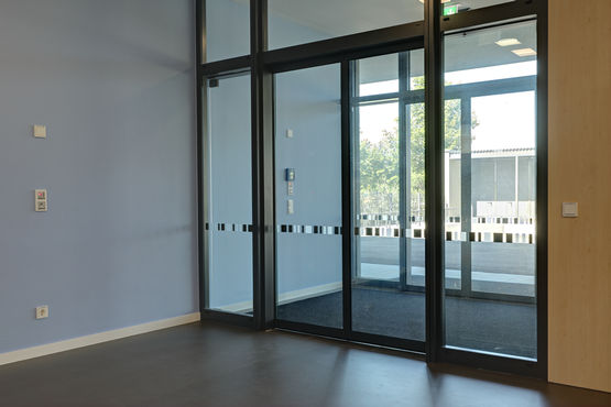 Interior view of entrance to Rheinhausen primary school, fitted with GEZE Slimdrive sliding door system for escape and rescue routes plus GEZE INAC access control system.