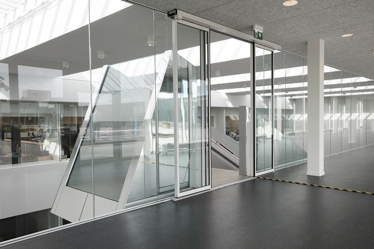 View of a room with straight and sloping glass fronts and a large glass door