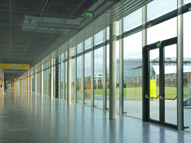 Sistema de puerta batiente de vidrio en la fachada de la nueva feria de muestras.