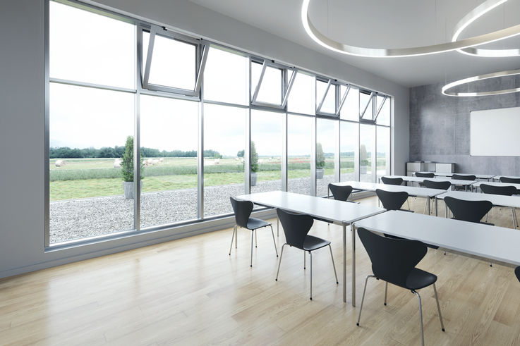 Une salle de classe avec une grande façade vitrée et des fenêtres automatisées. 