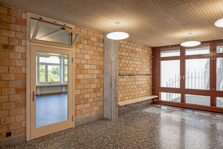 Ansicht des Schulflurs mit einer Glastür, an der das obere Fenster gekippt ist.