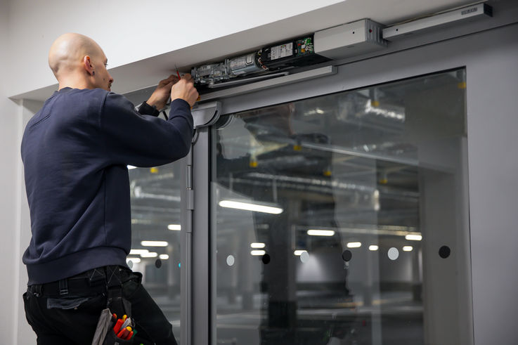 Servicetechniker von GEZE Service beim Einbau eines Türschließers an einer großen Glastüre