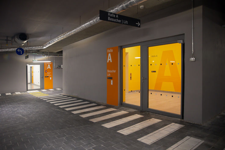 Nachtaufnahme der Tiefgarage mit Zugangstür zum Treppenraum und zur Halle