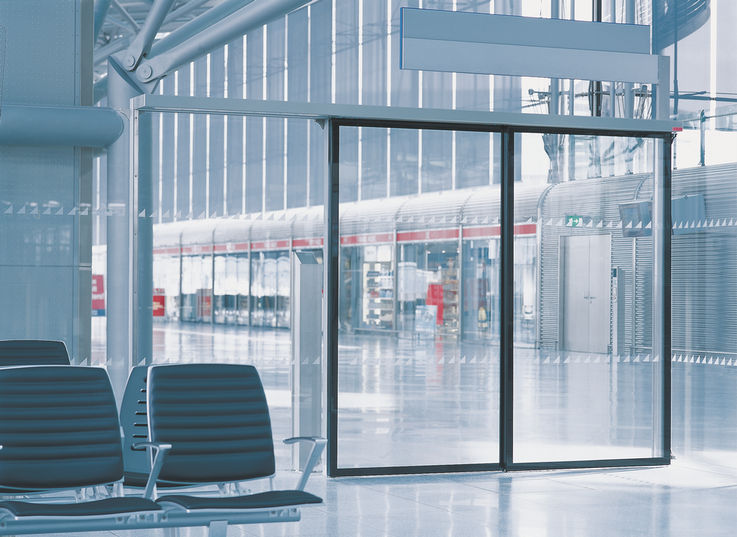 Automatic telescopic sliding door system for use in narrowest glass façades with two parallel surface mounted tracks, the door leaves lead and achieve high opening widths.