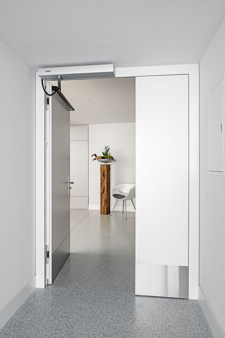 Una puerta cortafuegos de hoja simple abierta equipada con GEZE Powerturn F en la residencia Fux Campagna.